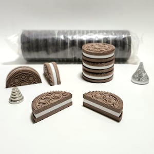 May include: A collection of miniature brown and white sandwich cookie replicas, including a stack of five, two halves, and a full package in clear plastic. Also included are a small silver-colored conical shape and a tiny stack of silver-colored discs.