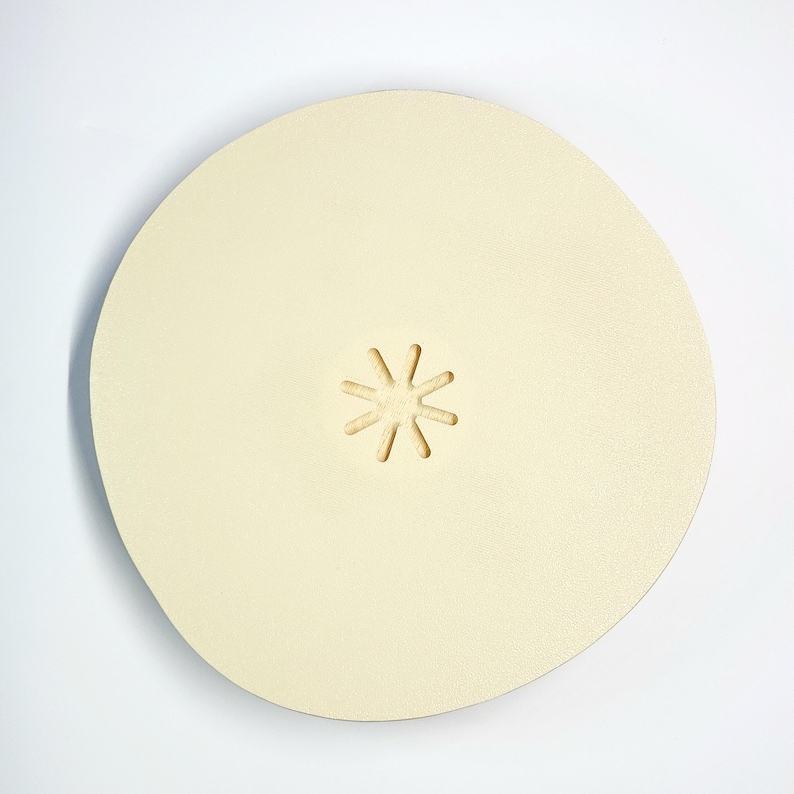 May include: A round, off-white sanding disc with a star-shaped cutout in the center.