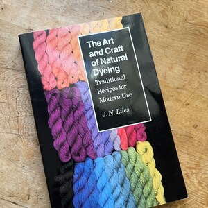 May include: A book titled "The Art and Craft of Natural Dyeing: Traditional Recipes for Modern Use" by J.N. Liles. The cover features a colorful display of yarn skeins in various shades of red, orange, yellow, green, blue, purple, and black.