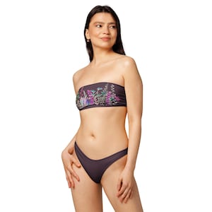 Puede incluir: Un traje de baño de dos piezas en color gris oscuro. La parte superior sin tirantes presenta un diseño floral con detalles en rosa, morado y verde. La parte inferior es de color gris oscuro a juego. El traje de baño está diseñado para nadar y tomar el sol.