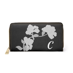 May include: Black leather wallet with a white floral design and the letter "C" in white.