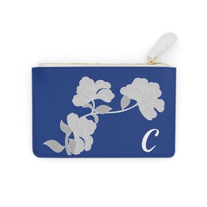 May include: A blue zippered pouch with a white floral design and the letter "C" in white.