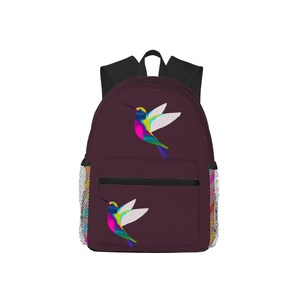 May include: A burgundy backpack featuring a colorful hummingbird design. The hummingbird has a yellow head, white wings, and a body of blue, pink, and green. The backpack has a black top, a front pocket, and mesh side pockets.