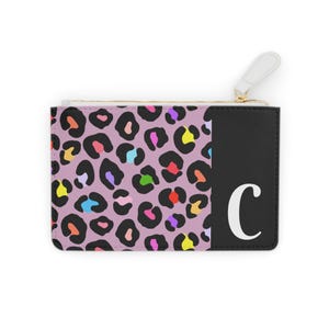 May include: A small purple and black leopard print zippered pouch with a black panel on the right side featuring a white letter "C".