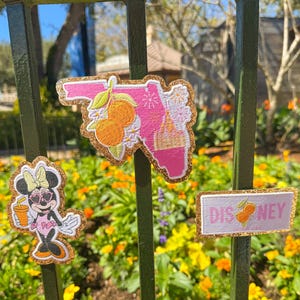May include: Three embroidered patches with gold glitter borders. One patch is a pink Florida outline with orange fruit and white flowers. Another is Minnie Mouse holding a drink. The third patch reads "DISNEY" with an orange.