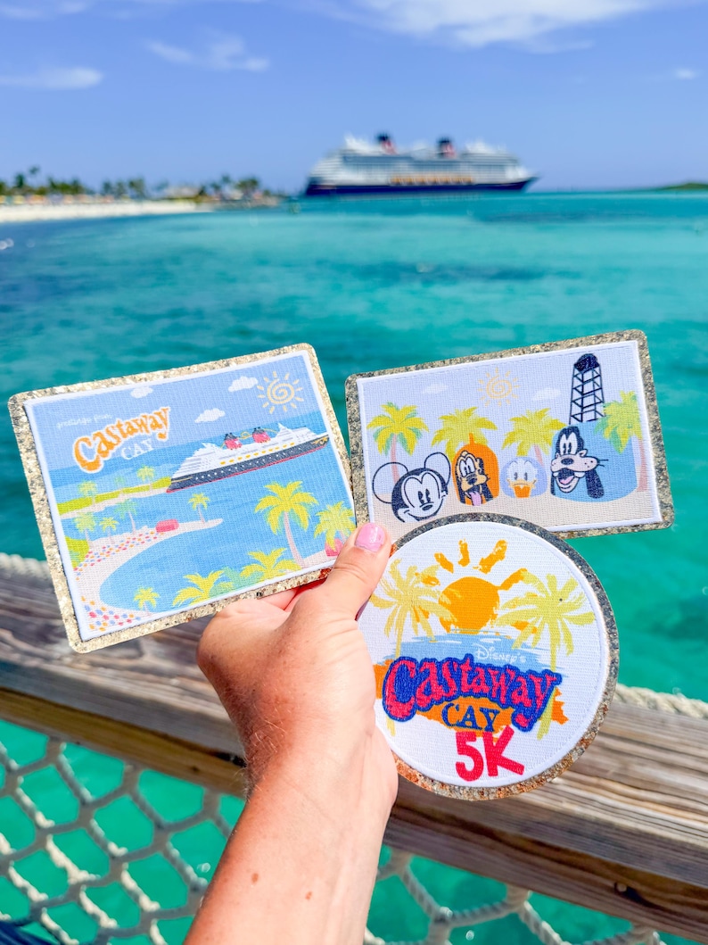 May include: Three embroidered patches featuring Disney themes. One rectangular patch shows a cruise ship and the text Castaway Cay. Another rectangular patch depicts Mickey, Pluto, Donald, and Goofy. A circular patch displays the text Castaway Cay 5K.