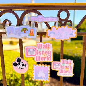May include: A collection of seven embroidered patches featuring Walt Disney World themes, including Mickey Mouse, park icons, and fireworks designs in pink, purple, and gold glitter accents, displayed on a brown metal railing.