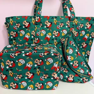 May include: A green tote bag, a rectangular zippered pouch, and a crescent-shaped crossbody bag, all featuring a repeating pattern of Disney characters wearing Santa hats and holly leaves against a dark green background with gold zippers.