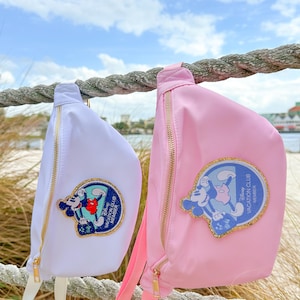 May include: Two fanny packs with Mickey Mouse and Minnie Mouse designs. The pink fanny pack has the text "Disney Vacation Club Member" on it. The white fanny pack has the text "Disney Vacation Club Member" on it.