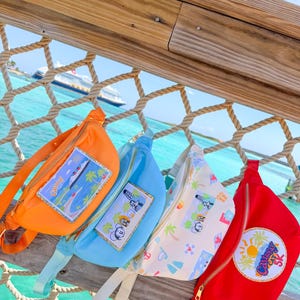 May include: Four fanny packs in orange, light blue, white with a colorful pattern, and red. The orange pack features a rectangular patch of a cruise ship. The blue and white packs have character patches, and the red pack has a circular Castaway Cay 5K patch.