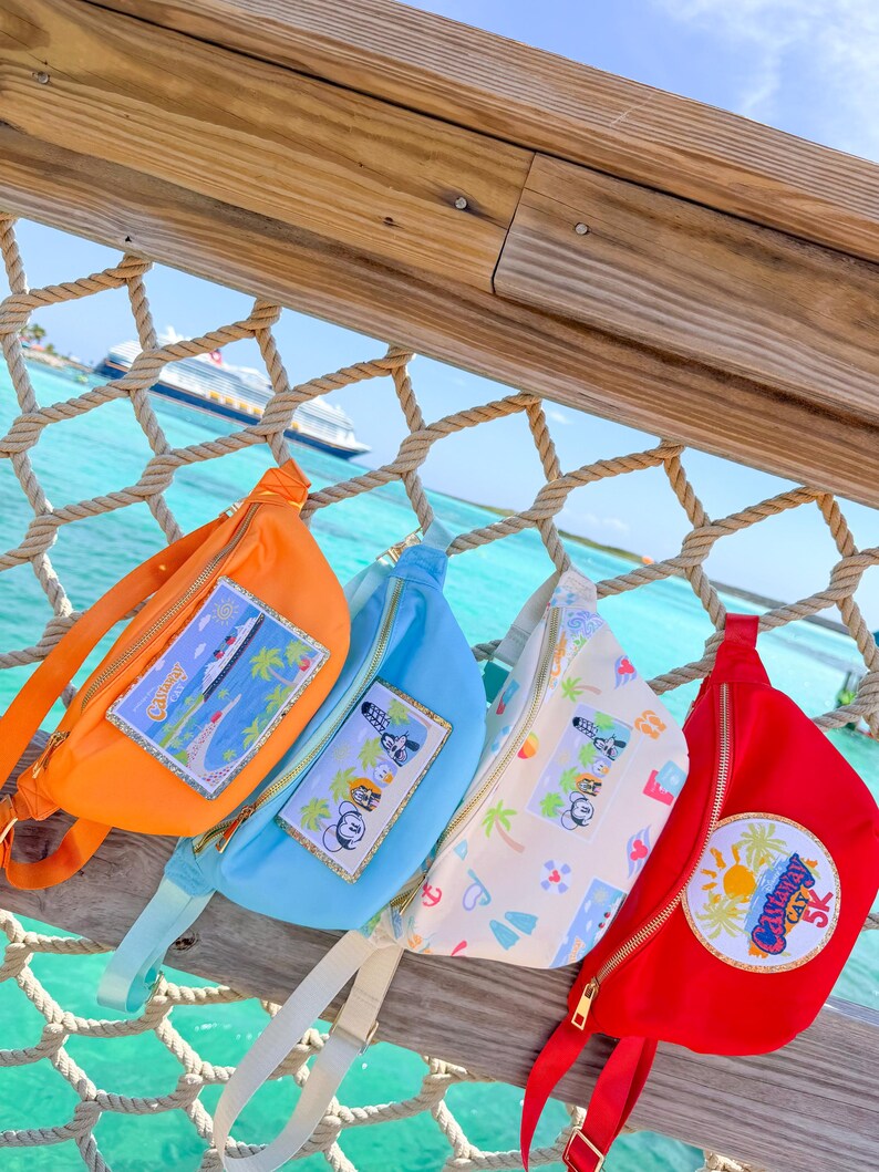 May include: Four fanny packs in orange, light blue, white with a colorful pattern, and red. The orange pack features a rectangular patch of a cruise ship. The blue and white packs have character patches, and the red pack has a circular Castaway Cay 5K patch.
