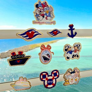 May include: A selection of Disney-themed pins and patches with nautical designs. The collection includes Mickey and Minnie Mouse, cruise ships, and anchors. Some pins feature the text "Literally just a cruise girl!" and "Ahoy!".