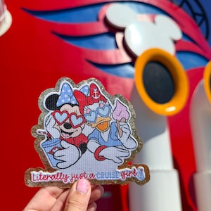 May include: A glittery embroidered patch featuring Minnie Mouse and Daisy Duck wearing heart-shaped sunglasses. Minnie holds a blue drink, while Daisy holds a pink ice cream cone. The text at the bottom reads, Literally just a CRUISE girl.