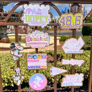 Puede incluir: Una colección de parches coloridos de eventos Run Disney. Los parches presentan varios diseños, incluyendo Mickey y Minnie Mouse, castillos y texto como "Dopey Challenge", "Disneyland Half Marathon Weekend" y "Coast to Coast Race Challenge".