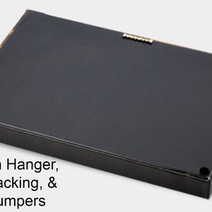 May include: The back of a framed artwork, featuring a black paper backing, sawtooth hanger, and wall bumpers. The frame has a black border with a gold accent. The text on the image reads: Sawtooth Hanger, Paper Backing, & Wall Bumpers.