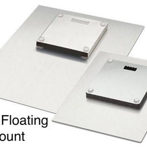 May include: Two metal floating mounts are shown, one larger than the other. Each has a square mounting plate with a keyhole for hanging and small rubber bumpers. The text "Metal Floating Mount" is visible.