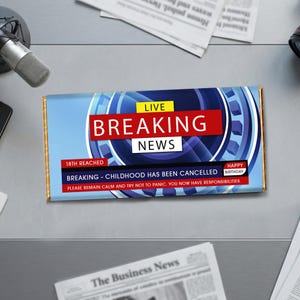 Könnte beinhalten: Eine Schokoladentafel mit einem blau-roten "Breaking News"-Design. Der Text enthält "18th Reached", "Breaking - Childhood Has Been Cancelled" und "Happy Birthday". Die Tafel hat eine goldfarbene Folienverpackung.
