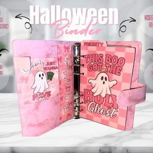 May include: Pink Halloween binder with a ghost graphic and the text "This Boo Got The Holy Ghost." The binder features a changeable design, budget tracker, custom labels, and two savings challenges. The binder is open, revealing interior pockets and pages.