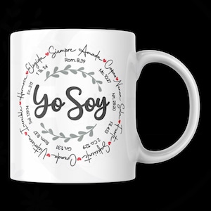 May include: White ceramic mug with the words "Yo Soy" in a stylized font. The mug features a circular design with Spanish words and Bible verses, including "Elegida" and "Siempre Amada". The handle is on the right side.