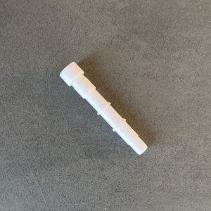 May include: White plastic connector with multiple sections. The connector is designed to connect two pieces of tubing together.