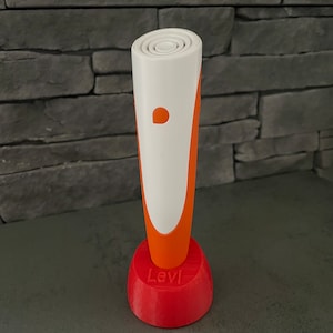 Könnte beinhalten: Ein weißer und orangefarbener 3D-Stift mit einem roten Sockel, auf dem "Levi" steht.