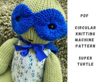 May include: A green knitted turtle wearing a blue eye mask and a blue ribbon. The turtle is wearing a white and blue patterned shirt. The image includes the text "PDF CIRCULAR KNITTING MACHINE PATTERN SUPER TURTLE".