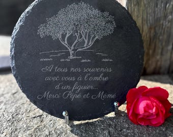 May include: A black slate plaque with a white engraved image of a tree and the text "A tous nos souvenirs avec vous à l'ombre d'un figuier... Merci Pépé et Mémé".