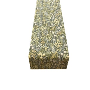 Pode incluir: Um corredor de mesa verde com um padrão floral em tons de amarelo e branco. O corredor é feito de um tecido macio e tecido e apresenta um delicado design floral.