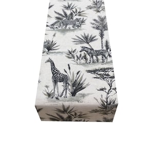 Könnte beinhalten: Ein beiger Tischläufer mit einem schwarz-weißen Safari-Druck mit Giraffen, Zebras, Leoparden und Palmen.