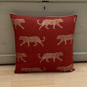 May include: Red cushion with a gold leopard print pattern.