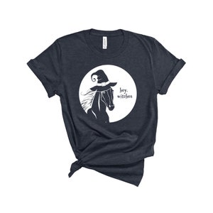 May include: A dark blue t-shirt with a white graphic of a horse wearing a witch's hat. The text "hey, witches" is printed below the horse.