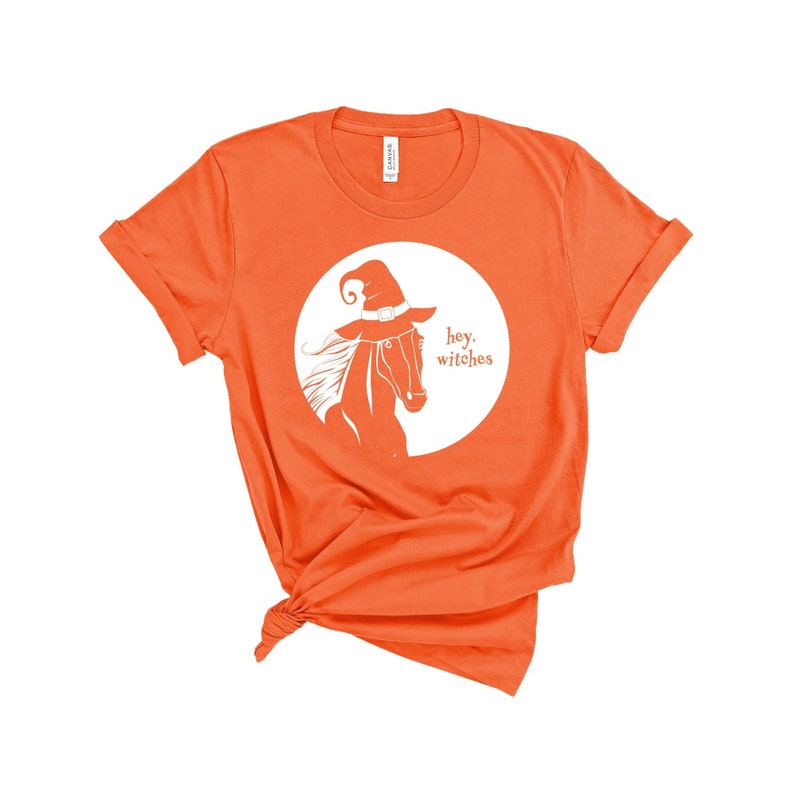 May include: Orange t-shirt with a white graphic of a horse wearing a witch hat and the text "hey, witches".