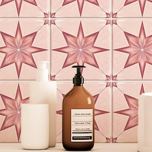 May include: A wall featuring a pink and burgundy starburst tile pattern. A brown bottle with a black pump dispenser and white label sits on a white surface, alongside two white ceramic containers. The tile design is repeated in the background.