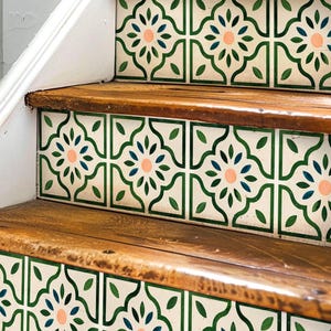 May include: Wooden staircase with decorative tiles. The tiles feature a repeating pattern of green leaves, blue accents, and a central peach-colored flower on a cream background. The steps are made of natural wood.