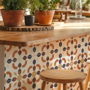 May include: A kitchen island with a wooden countertop and decorative tile. Terra cotta pots with green plants sit on a wooden slab. A wooden stool is in the foreground. The tile has a repeating pattern in orange, blue, and yellow.