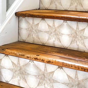May include: Close-up of wooden stairs with a white and grey geometric patterned tile design on the risers. The tile pattern features a repeating starburst design.