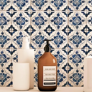 May include: Two bottles of liquid soap with white labels and pumps, sitting on a white countertop in front of a blue and white patterned tile wall.
