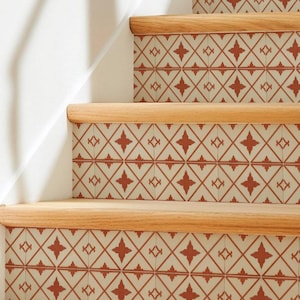 May include: A staircase with wooden steps and risers, adorned with patterned tiles. The tiles display a repeating design of red crosses and diamond shapes on a cream background. The wooden steps have a natural finish.
