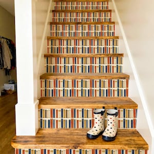 Può includere: Scala in legno con alzatine decorate con un motivo ripetuto di strisce verticali rosse, blu navy e oro. Un paio di stivali da pioggia bianchi con motivi a cuore e pois sono sul gradino inferiore.