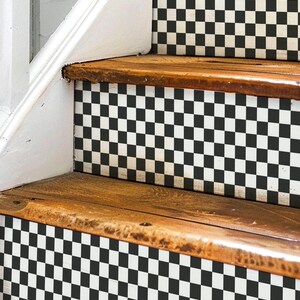 May include: Wooden staircase with black and white chequered risers. The steps are made of natural wood, and the risers feature a classic checkerboard pattern. The staircase is part of a home interior.