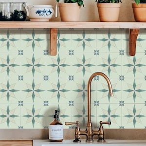 May include: Kitchen backsplash featuring a repeating star pattern in light green and blue. A copper tap and white sink are in the foreground. Wooden shelves hold potted plants and decorative items.
