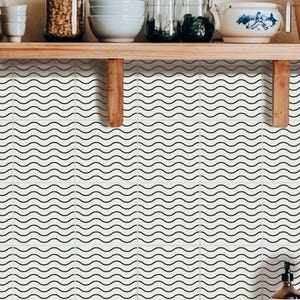 May include: White tile backsplash with a repeating black wavy line pattern. The kitchen features wooden shelves with jars, bowls, and a decorative teapot. A soap dispenser is visible on the counter.