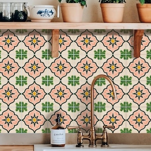 May include: A kitchen scene with patterned tiles forming a backsplash. The tiles display a repeating floral design in cream, pink, green, and yellow. A brass tap and white sink are visible, with shelves above holding plants and kitchen items.