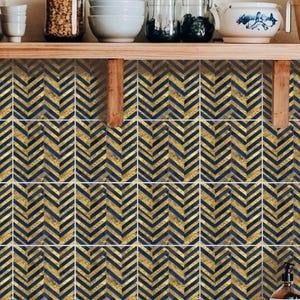 Peut inclure: Carrelage décoratif de cuisine avec un motif chevron bleu marine et doré. Les carreaux sont disposés en grille et créent un design visuellement attrayant. Les carreaux sont installés sur un mur, avec des étagères en bois et des articles de cuisine en arrière-plan.