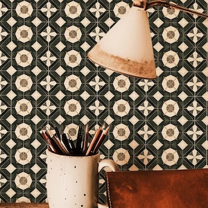 Peut inclure: Un mug en céramique blanche à pois noirs rempli de crayons est posé sur une table en bois devant un papier peint à motifs noir et blanc. Un porte-documents en cuir marron et un carnet sont également sur la table. Une lampe vintage avec un abat-jour blanc est placée au-dessus du mug.