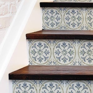Può includere: Scala con gradini in legno marrone scuro e alzatine decorate con piastrelle a motivi floreali nei toni del blu e del grigio. Le piastrelle presentano un design circolare con un fiore centrale e foglie.
