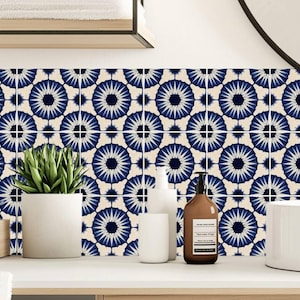 May include: A wall covered in square tiles featuring a repeating pattern of dark blue, star-like floral motifs on a cream background. The tiles are arranged in a grid, creating a continuous geometric design across the surface.