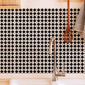 Könnte beinhalten: Schwarze und weiße Fliesen mit Rautenmuster als Spritzschutz in einer Küche mit einem weißen Doppelwaschbecken und einem silbernen Wasserhahn.