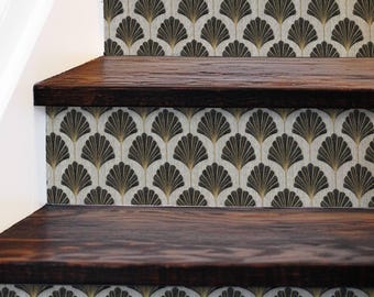 May include: A staircase featuring dark wood steps and risers. The risers are adorned with a repeating fan-shaped pattern in black and gold against a light backdrop, creating a vintage art deco style.