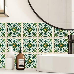 Può includere: Arredamento bagno con piastrelle decorate con un motivo floreale in verde, giallo e bianco. Le piastrelle sono installate sopra un piano di lavoro con un lavandino bianco, dispenser di sapone e uno specchio.